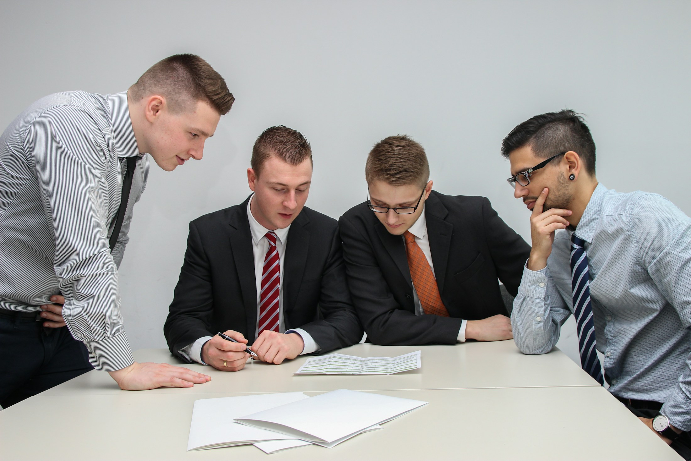 Mehrere Personen besprechen gemeinsam ein Dokument am Tisch, Symbolbild für Konfliktlösung im Unternehmen