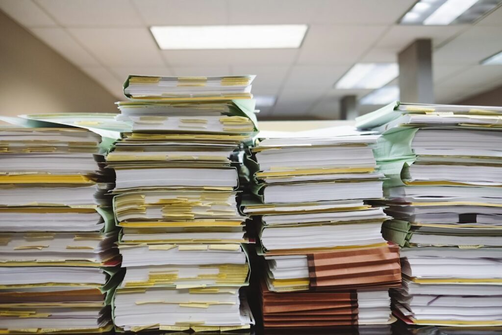 Stapel aus Dokumenten und Aktenordnern im Büro